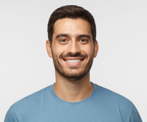 Close Up Portrait Of Young Smiling Handsome Guy In Blue T Shirt Isolated On Gray Background